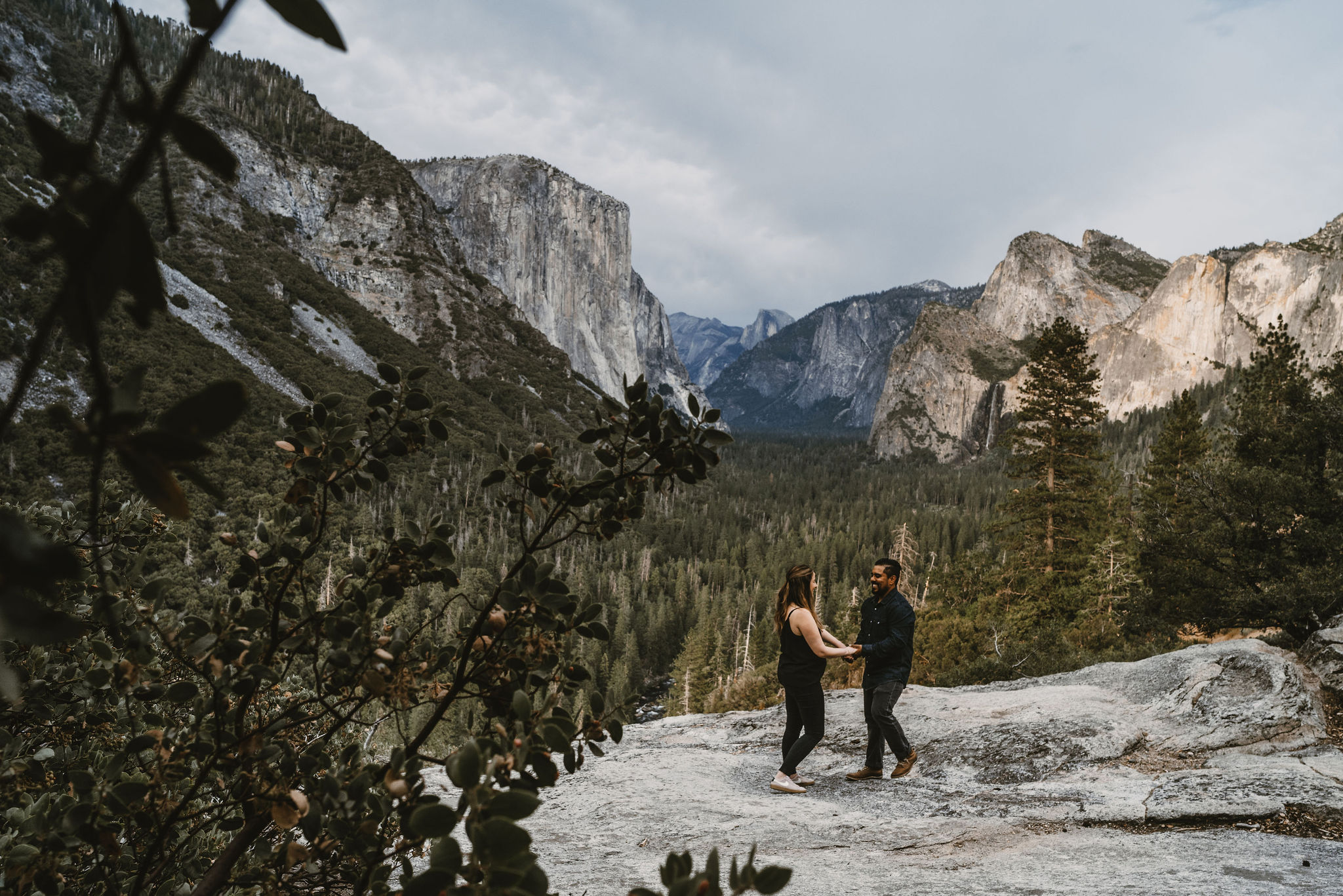 Yosemite Engagement Photography of a couple on boulders above the yosemite valley. Half dome and taft toint can be seen in the background.