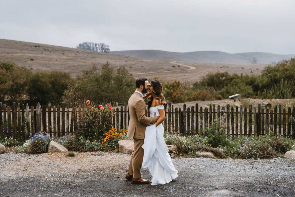 Bride and groom share a joyful embrance amist the rolling hills during first look at stemple creek ranch