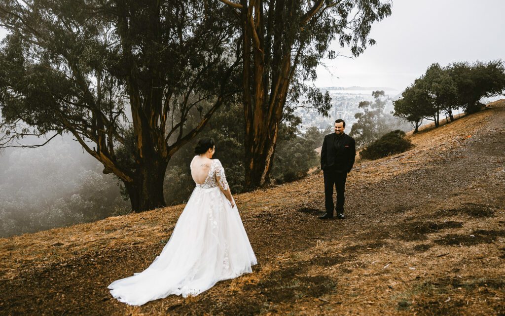 groom smiles as he sees his bride during a foggy first look at grizzly peak in berkeley california