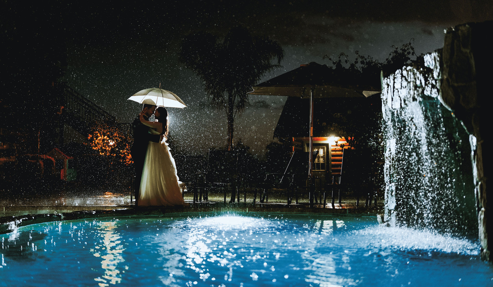 romantic portrait of bride and groom holding an ubrella in the rain at Purple Orchid in Livermore california